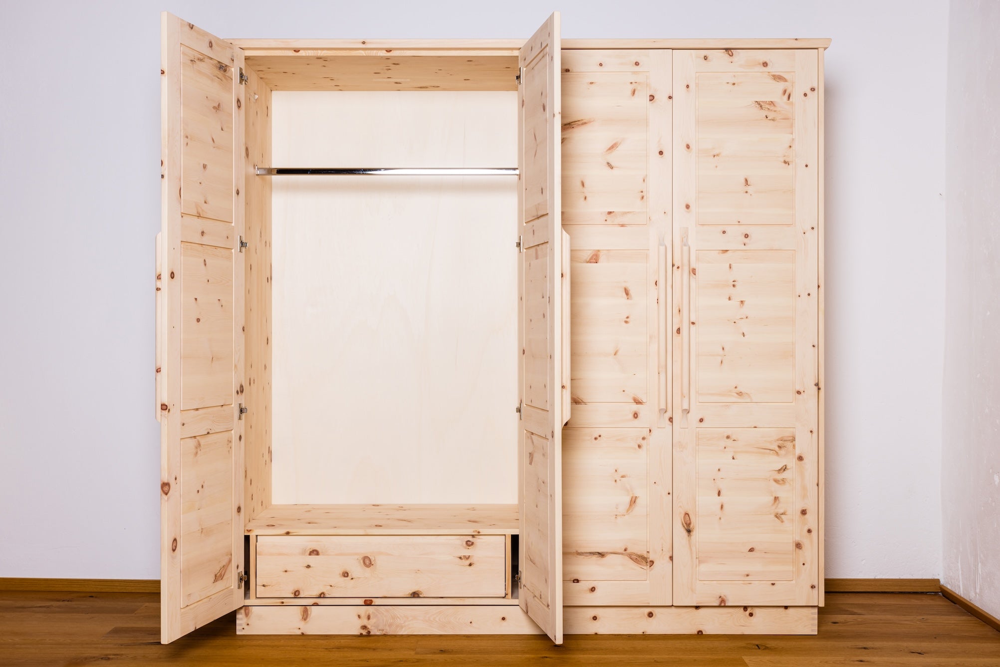 Kleiderkasten aus Zirbe mit 4 Drehtüren geöffnet, Holzoberfläche und praktische Aufbewahrungslösungen.