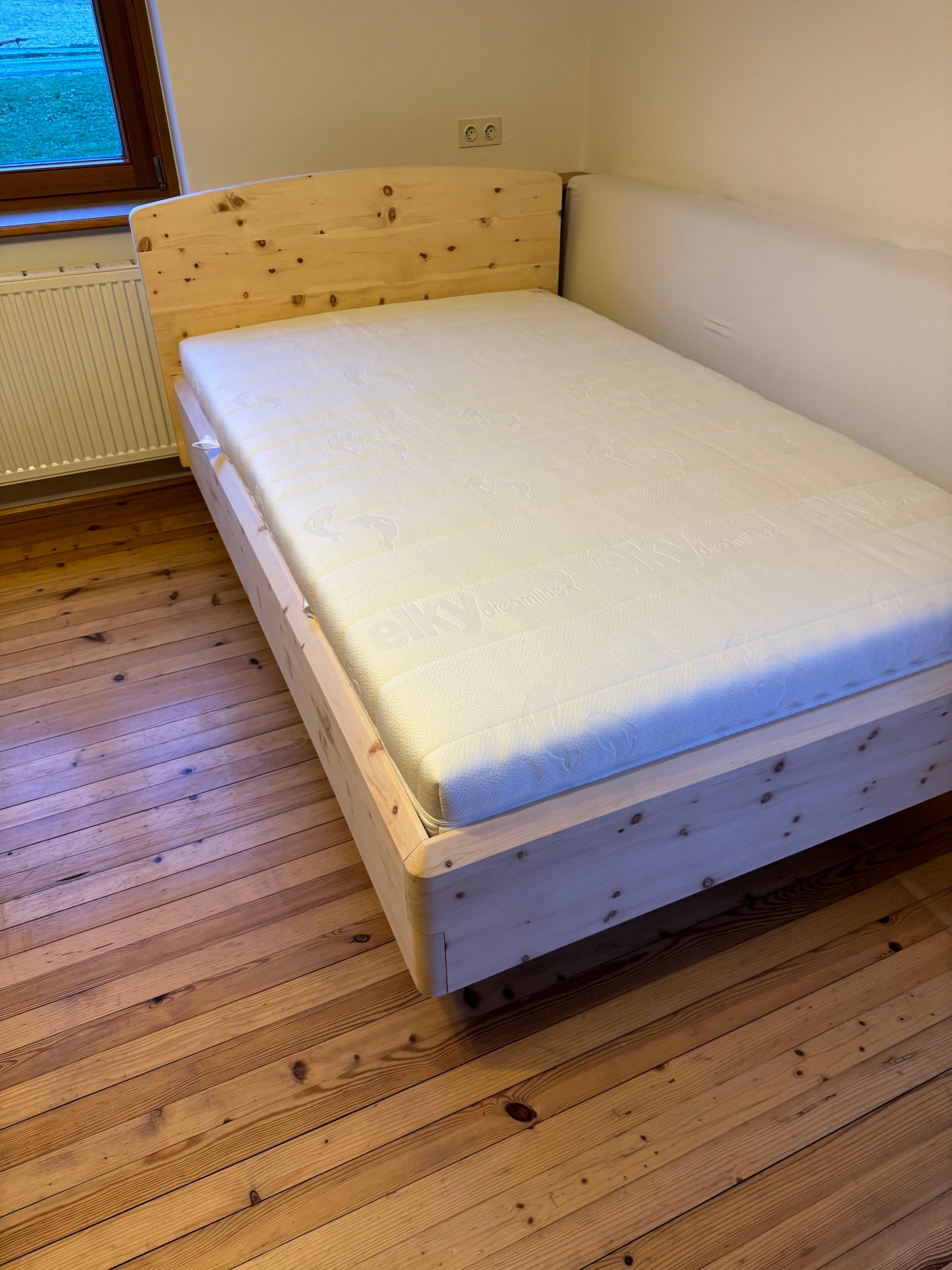 Facettenkante am Bettrahmen aus Zirbenholz in einem gemütlichen Schlafzimmer.
